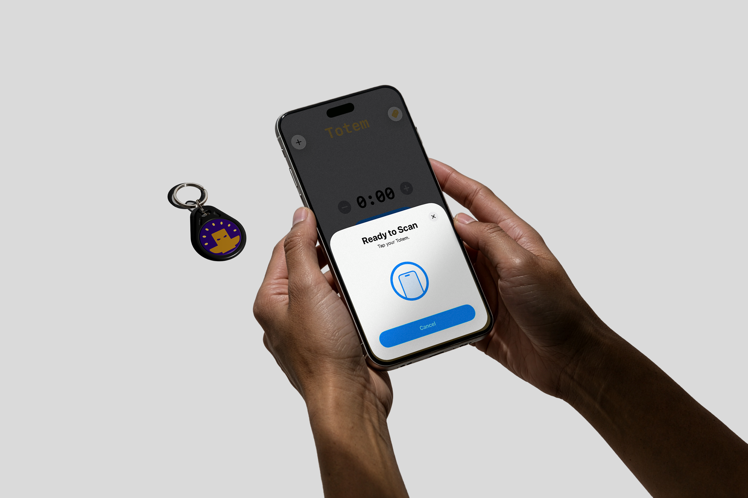 Person holding a phone with our Totem app tapping to our purple keychain Totem with a yellow logo on a gray background. Used to aid focus for ADHD and students. Totem Focus.